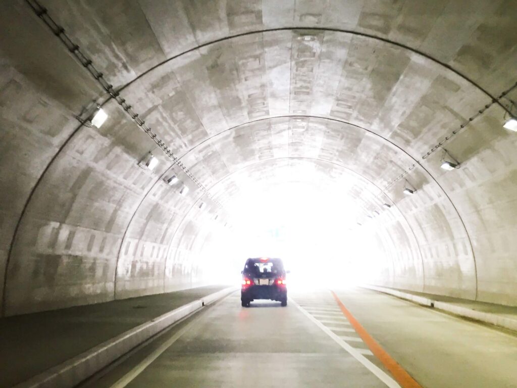 トンネルの向こうの光に向かう一台の車