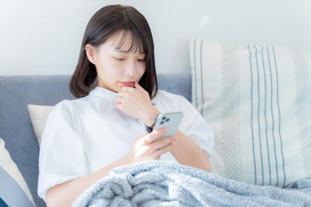 スマホを見ながら考える女性