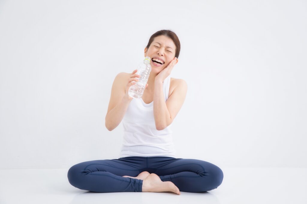 ヨガをしながら水分補給をする若い女性